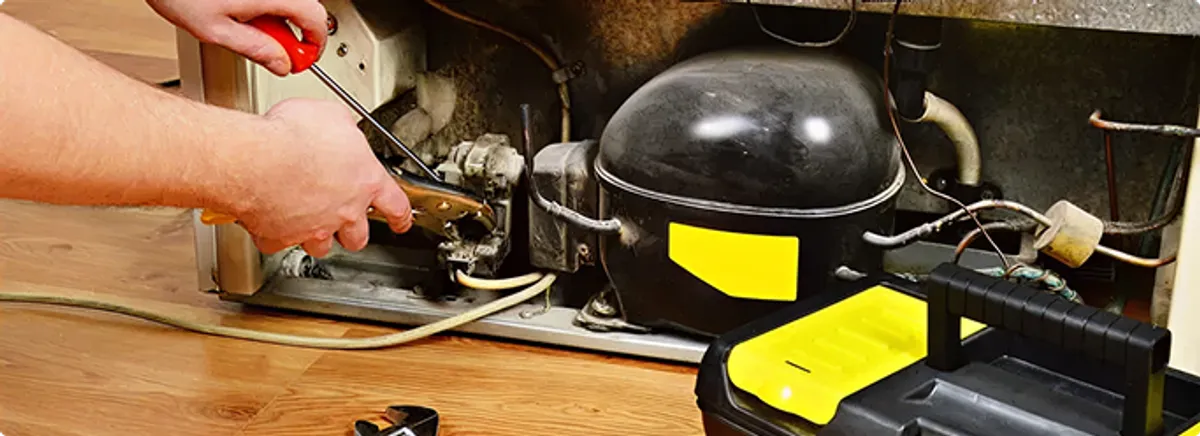 Refrigerator repair technician fixing the compressor and wiring in Ogden, UT